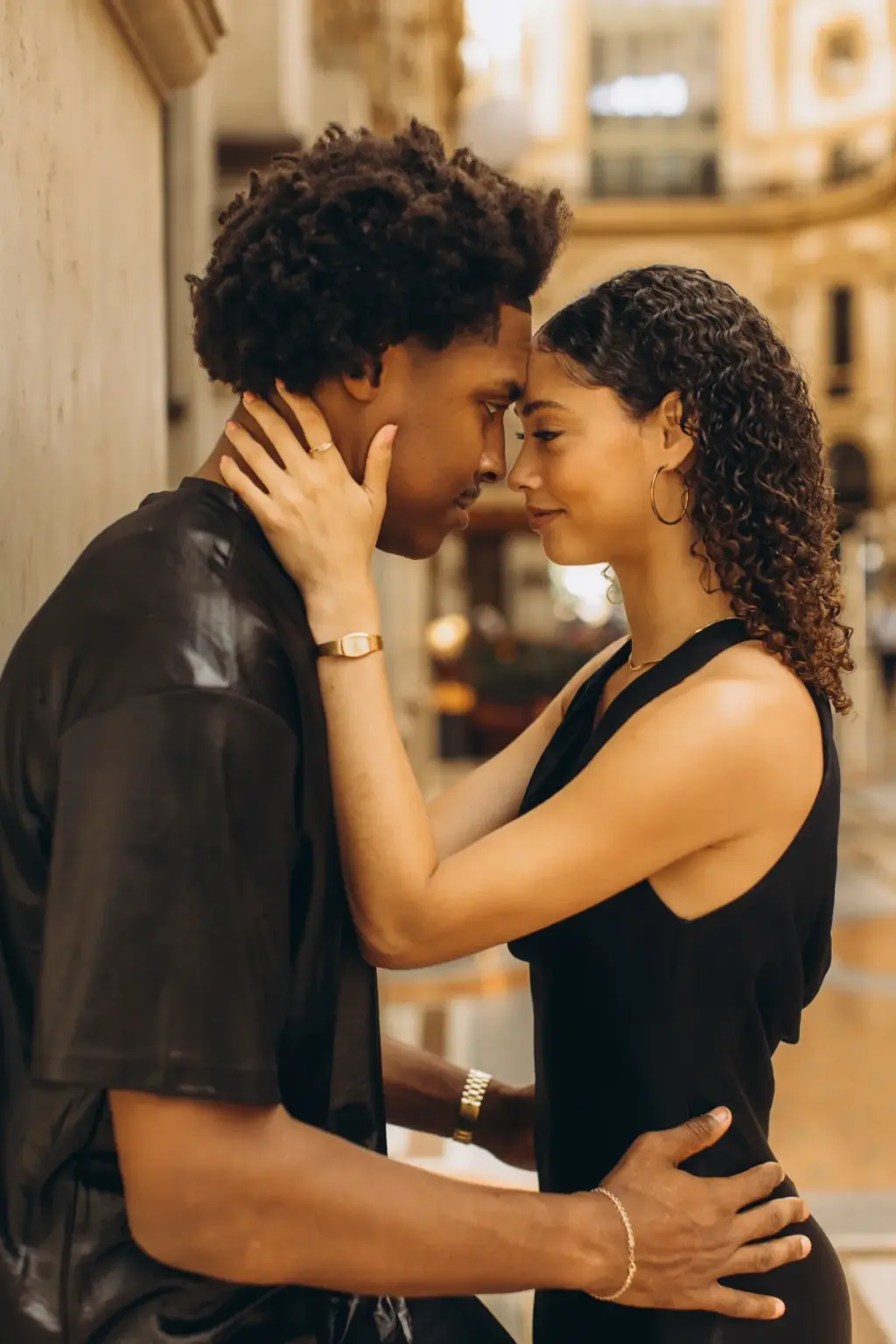 Foreheads touching, a man and woman hold each other close in a quiet corner of the Galleria, her hand resting along his jaw.