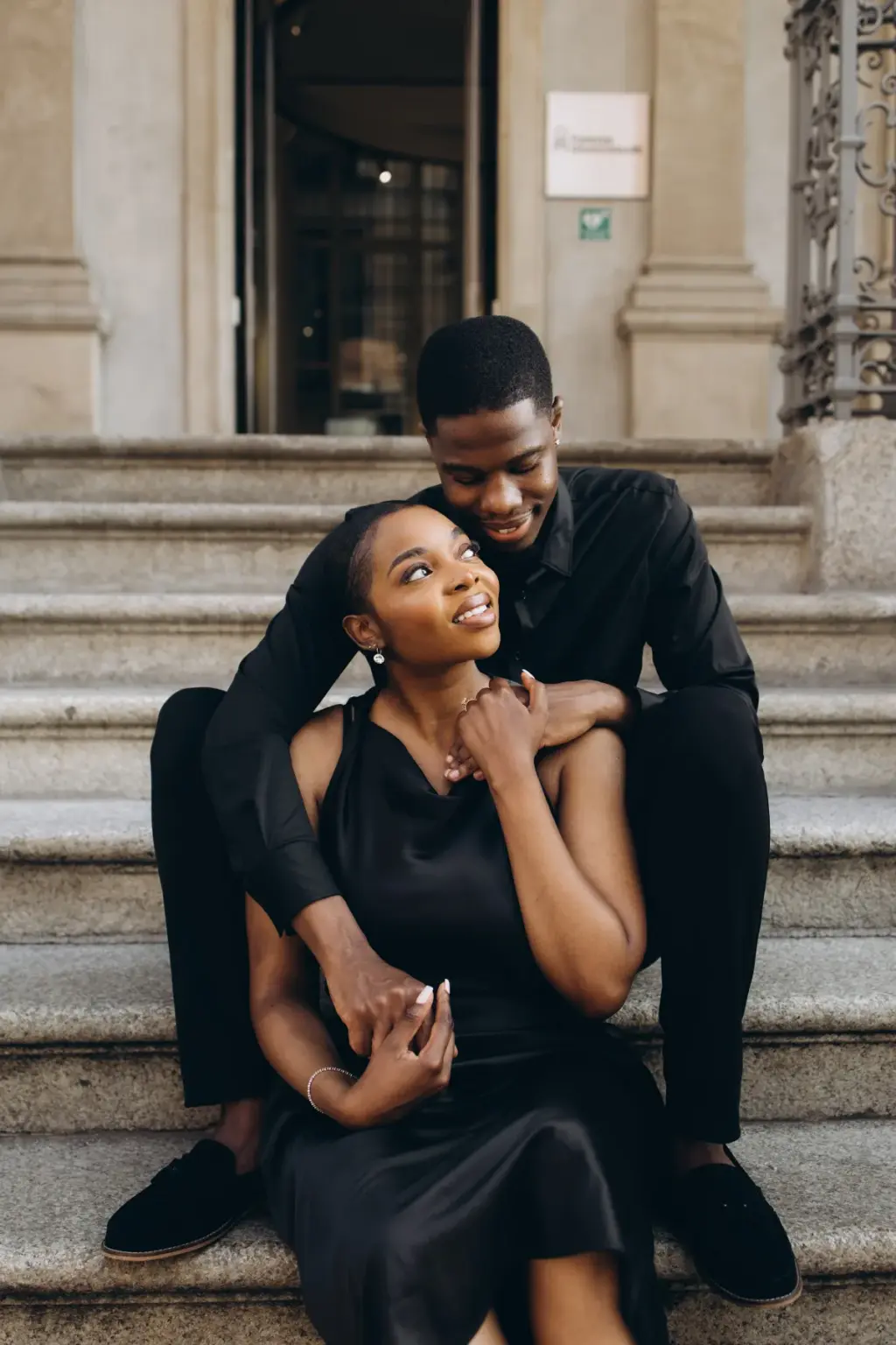 On the palazzo steps she tips her head back to laugh up at him, holding his hand as he leans down over her shoulder.
