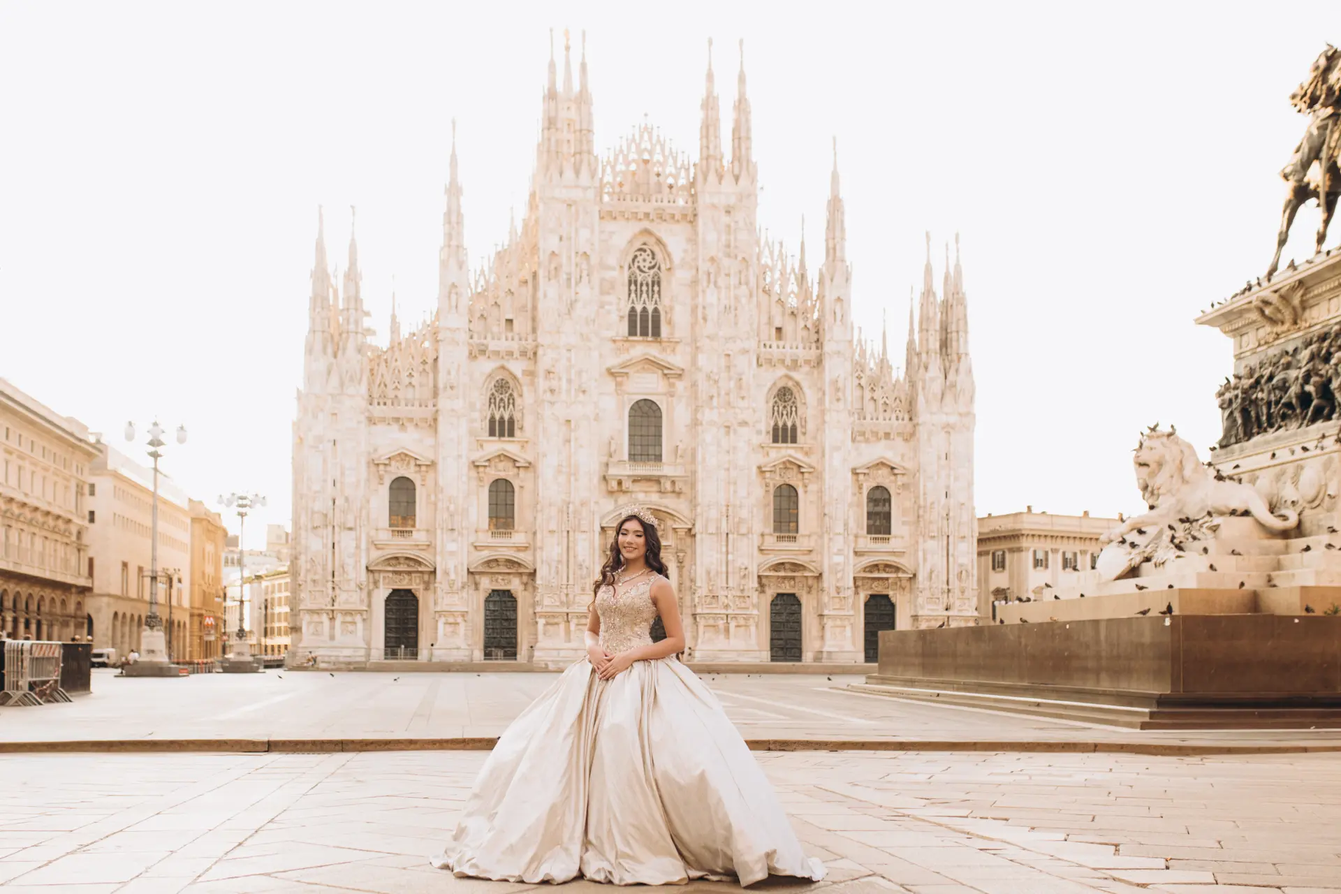A woman in an ivory ball gown stands alone in the empty Piazza del Duomo in Milan in the early morning