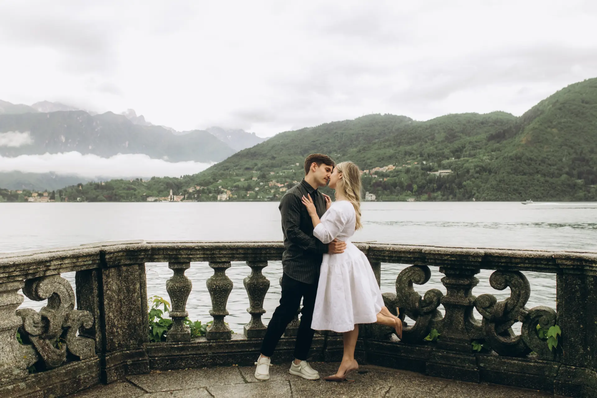 Couple kissing on a stone villa balustrade above Lake Como
