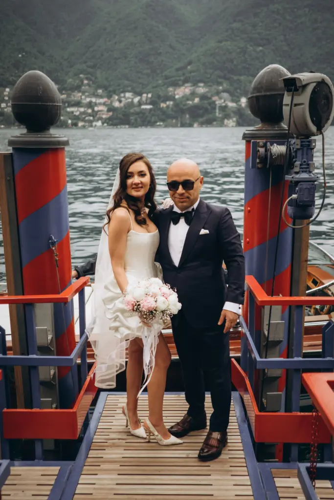 Bride and groom on a boat dock with striped Riva mooring poles on Lake Como