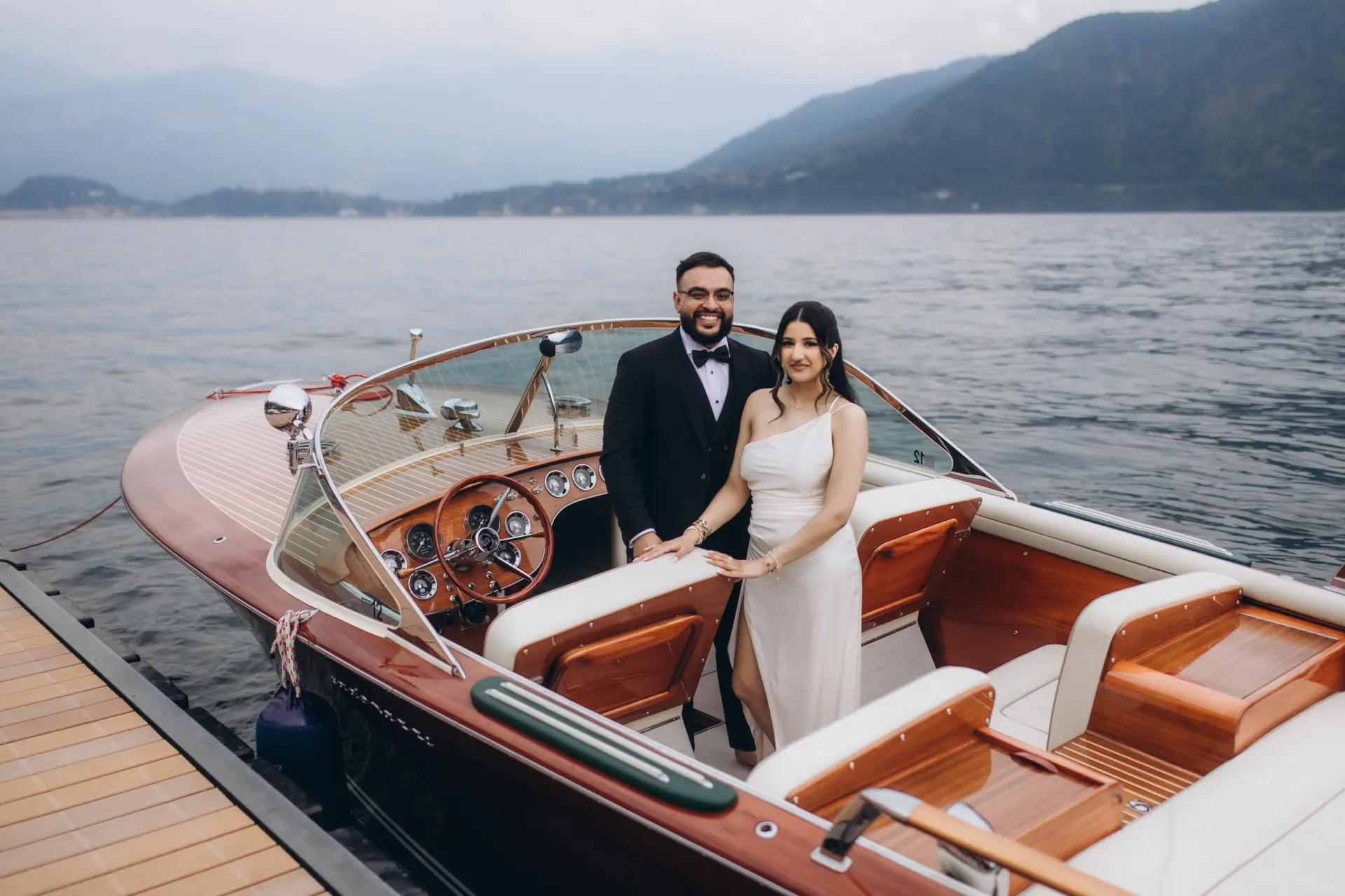 Bride and groom on a classic wooden boat at the dock, Lake Como