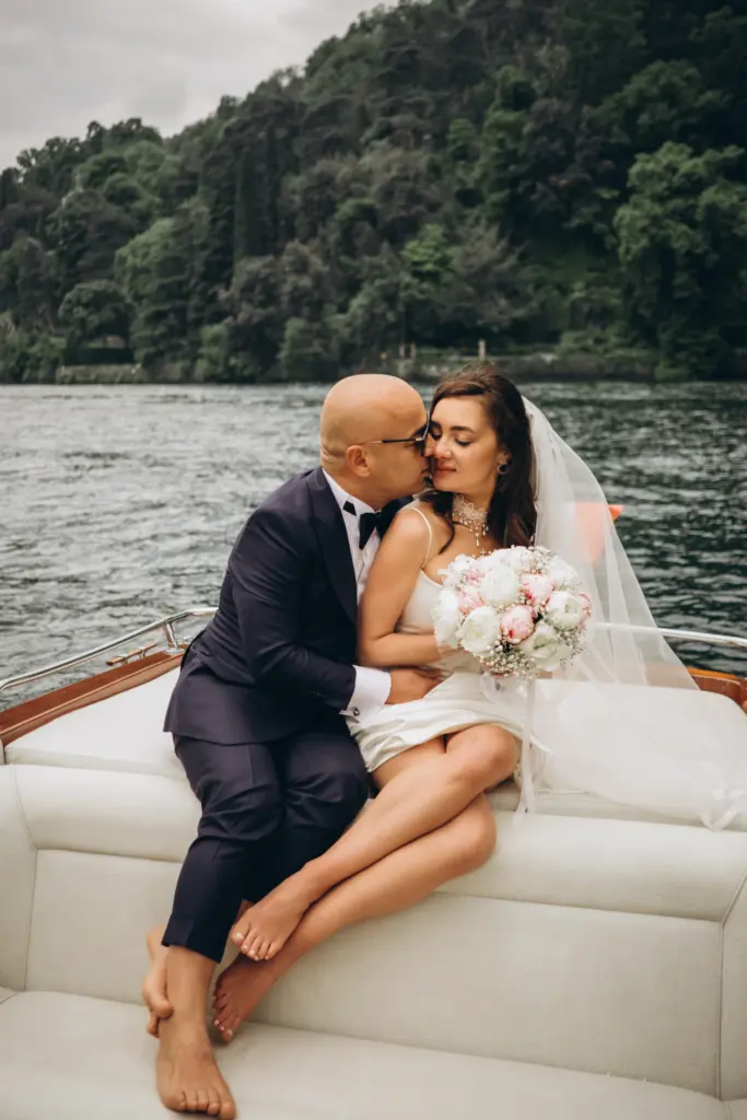 Bride and groom on a Riva boat on Lake Como, her bouquet in her lap