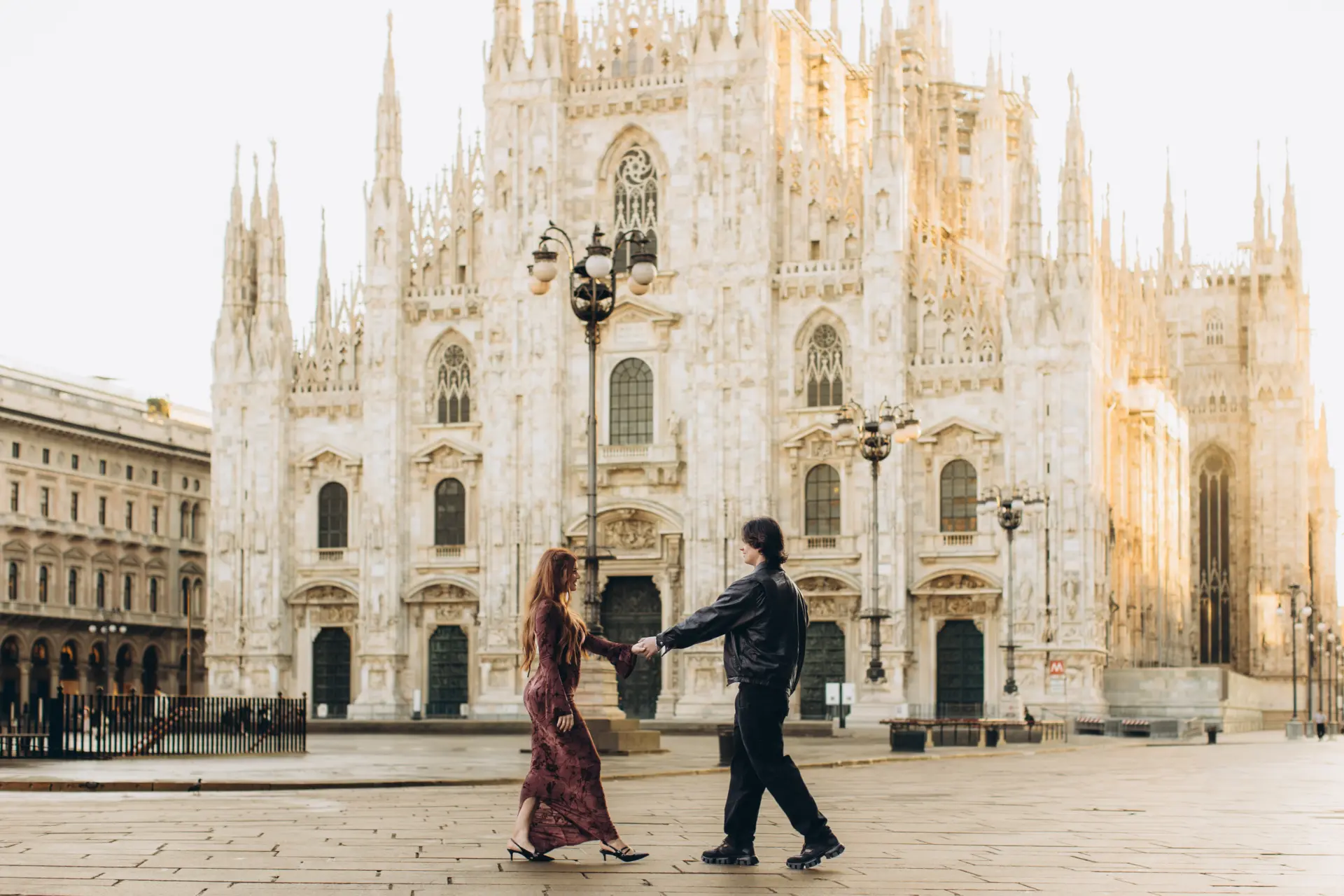 Couple walking hand in hand in front of the Duomo, Milan