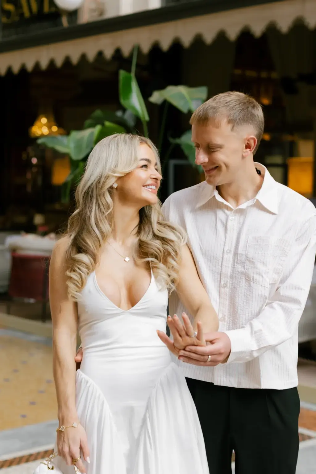 Beside the Savini terrace in the Galleria, a man holds his partner's ringed hand as she laughs and leans into him.